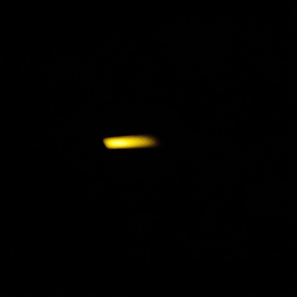 Dark, low-key photograph of a sleek smartphone in deep shadow with a single warm highlight along the edge, moody charcoal and muted gold tones.