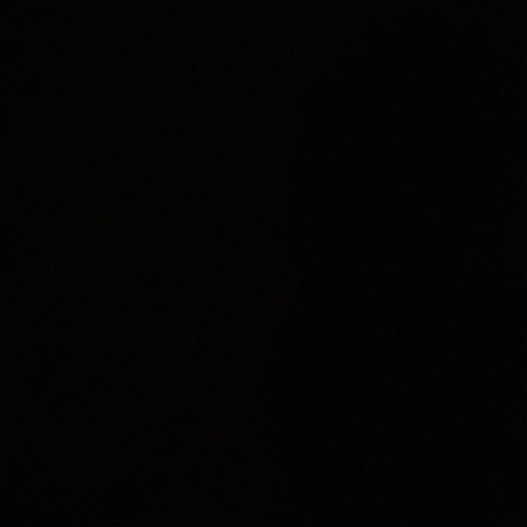 Dark, low-key photograph of stacked retail boxes in shadow, deep charcoal tones with a single edge of warm gold light.